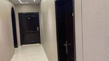 A hallway with a tiled floor, a door on the right, and a door at the end.