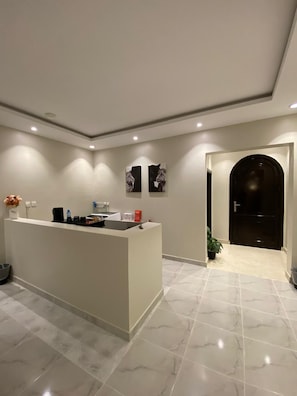 Una cocina moderna con encimera de mármol, iluminación empotrada y una puerta oscura que da a otra habitación.