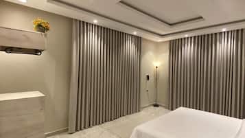 A modern hotel room with a large bed, a built-in wardrobe, and a floor lamp.