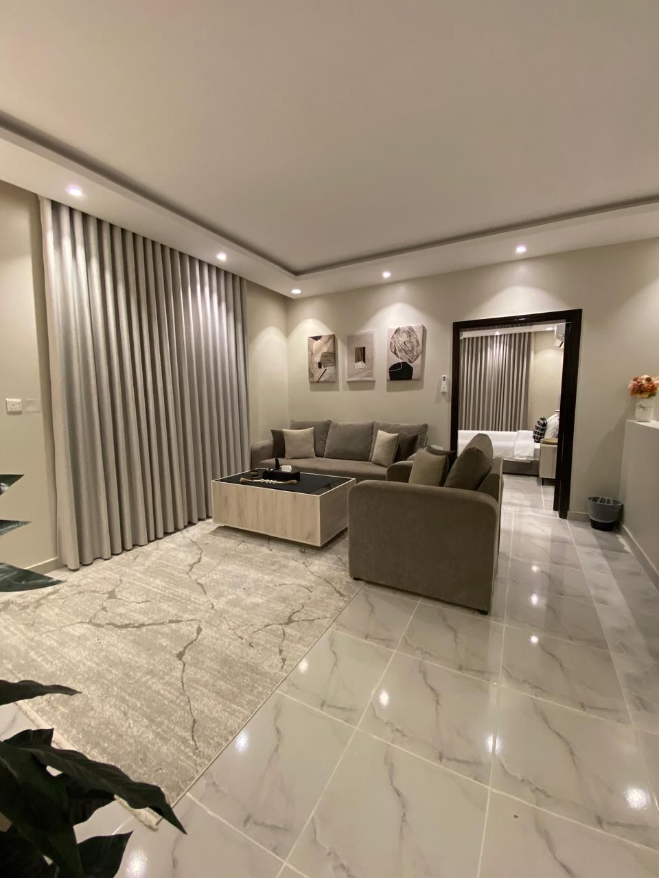 A modern living room with a sofa, coffee table, and a dining area with a table and chairs.