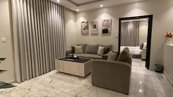 A modern living room with a sofa, coffee table, and a dining area with a table and chairs.