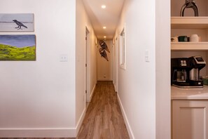 A narrow hallway with wooden flooring, white walls, and a coffee machine on a counter. - Walk to Downtown Lake Placid: 3BR Condo, Fireplace & Woodland Views (Lake Placid)