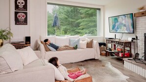 Ein gemütliches Wohnzimmer mit großem Fenster, Fernseher und Kamin.