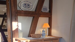 Un mobiletto in legno con cassetti, una sedia bianca e un tavolo con una lampada.