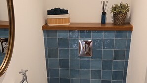 Un bagno con lavandino bianco, WC e uno specchio. Sopra il lavandino ci sono due quadri appesi al muro.