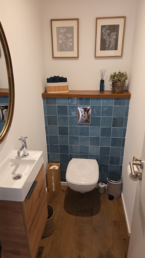 A bathroom with a white sink, a toilet, and a mirror. There are two framed pictures on the wall above the sink. - Vrbo Property (Scheibenhard)