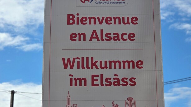 Segnale di benvenuto per l'Alsazia, con un logo e testo in alsaziano e francese.