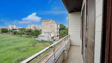 Un balcón con vista a un campo cubierto de césped y edificios a lo lejos.