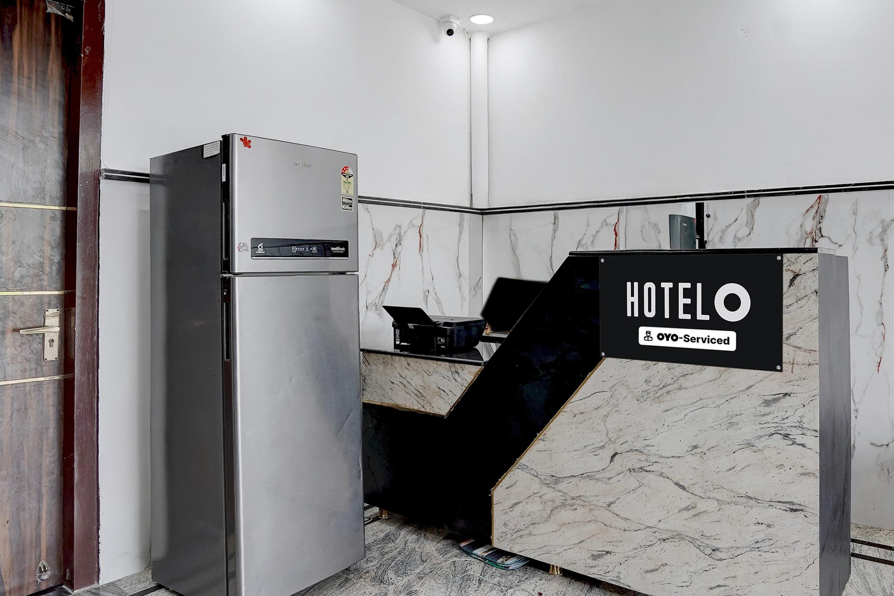 En hotellobby med en vägg av marmor, en receptionsdisk och ett kylskåp.