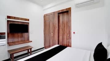 Una habitación de hotel con una cama, un banco, un televisor montado en la pared y un armario.