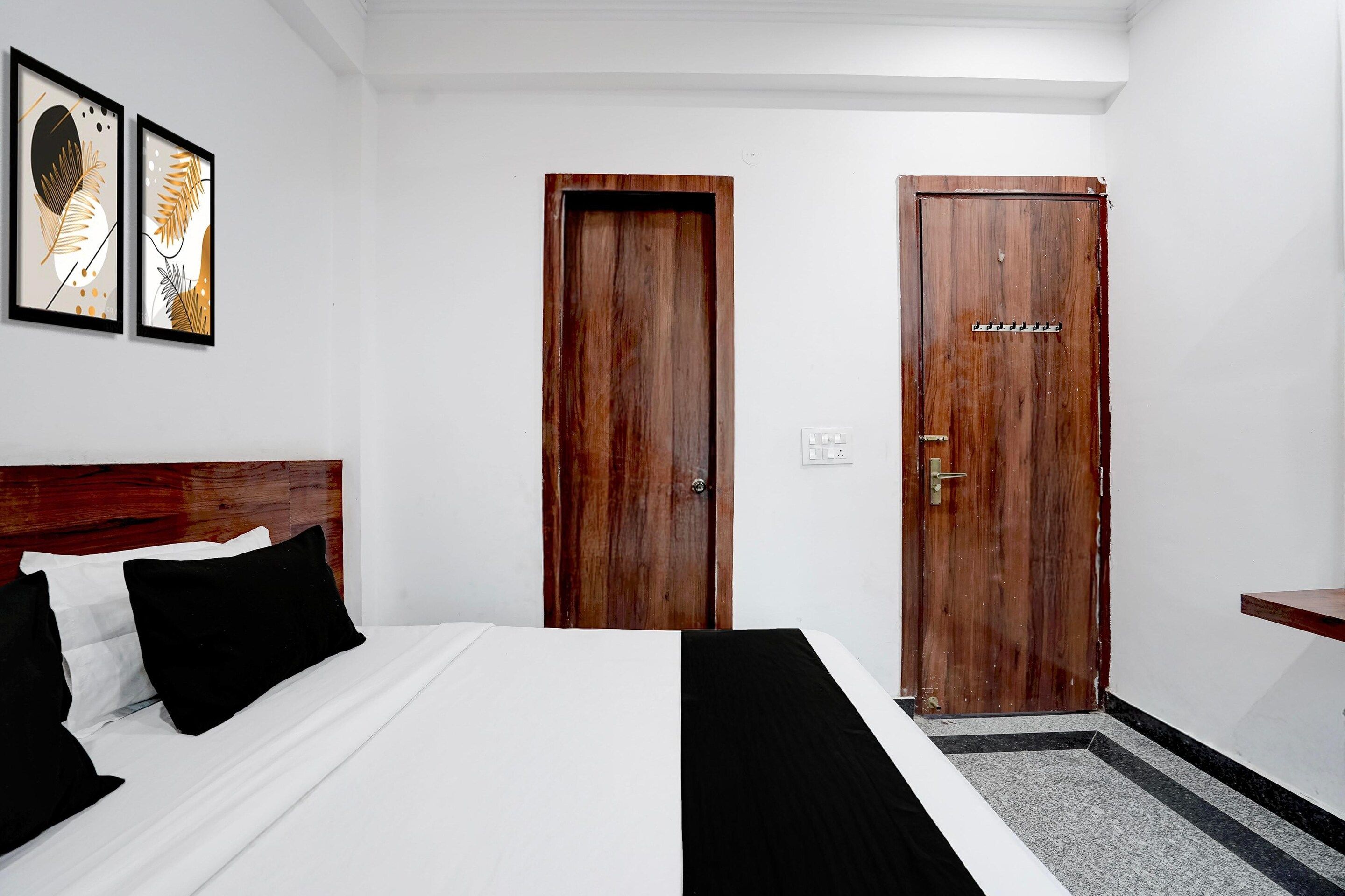 Ein Hotelzimmer mit einem Bett, zwei Türen, einem Kopfteil und einem kleinen Tisch.