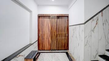 Un pasillo con puerta de madera, paredes de mármol y una escalera de mármol.