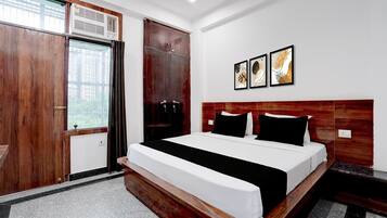 Ein Hotelzimmer mit einem großen Bett, einem Holzschrank und einem Fenster mit Vorhängen.