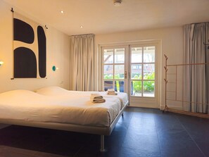 Ein Hotelzimmer mit einem großen Bett, einer Schiebetür zum Außenbereich und Blick auf Grünflächen.