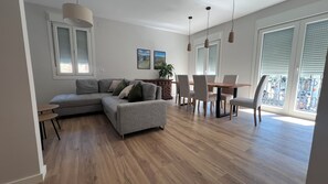 Een moderne woonkamer met een modulaire bank, een eettafel, stoelen en uitzicht op de natuur.