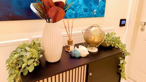 Una consolle decorativa con un vaso di fiori, un mappamondo e una piccola statuina.