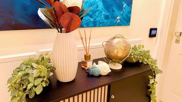 Une console décorative ornée d’un vase de fleurs, d’un globe terrestre et d’une petite statuette.