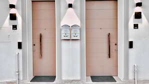 Facciata di un edificio con due porte simmetriche, ciascuna dotata di maniglia e un piccolo oblò sopra.