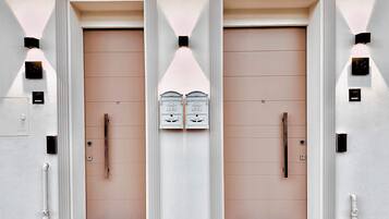 Une façade d’immeuble avec deux portes symétriques, chacune dotée d’une poignée et d’une petite fenêtre au-dessus.