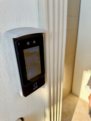 Cerradura digital instalada en una pared blanca con textura, probablemente para un hotel o apartamento.