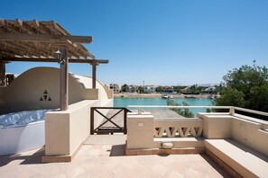 A poolside area with a pergola, a view of a calm body of water, and a clear sky. - Vesta Luxury Apartment -1br - New Nubia (El Gouna)