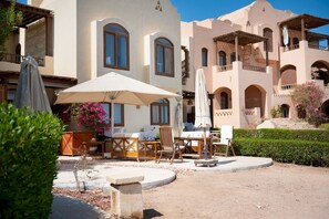 A courtyard with outdoor seating, a pool, and a building with multiple balconies. - Vesta Luxury Apartment -1br - New Nubia (El Gouna)
