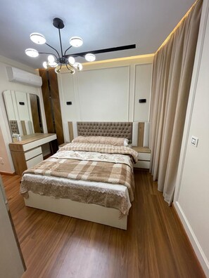Ein Schlafzimmer mit einem Bett, Nachttischen, einem Spiegel und einer Deckenleuchte.