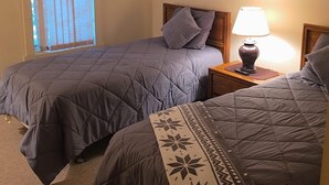 A bedroom with two beds, a nightstand with a lamp, a window with blinds, and a framed picture on the wall. - Perfect 2-bedroom house in amazing Lake Harmony getaway (Lake Harmony)