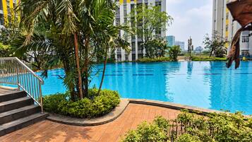 A swimming pool surrounded by greenery and modern buildings.