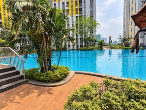 A swimming pool surrounded by greenery and modern buildings.