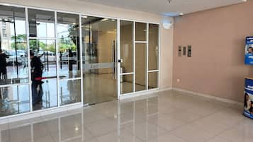 Un vestíbulo moderno con puertas de cristal, piso de baldosas y un ascensor empotrado en la pared.
