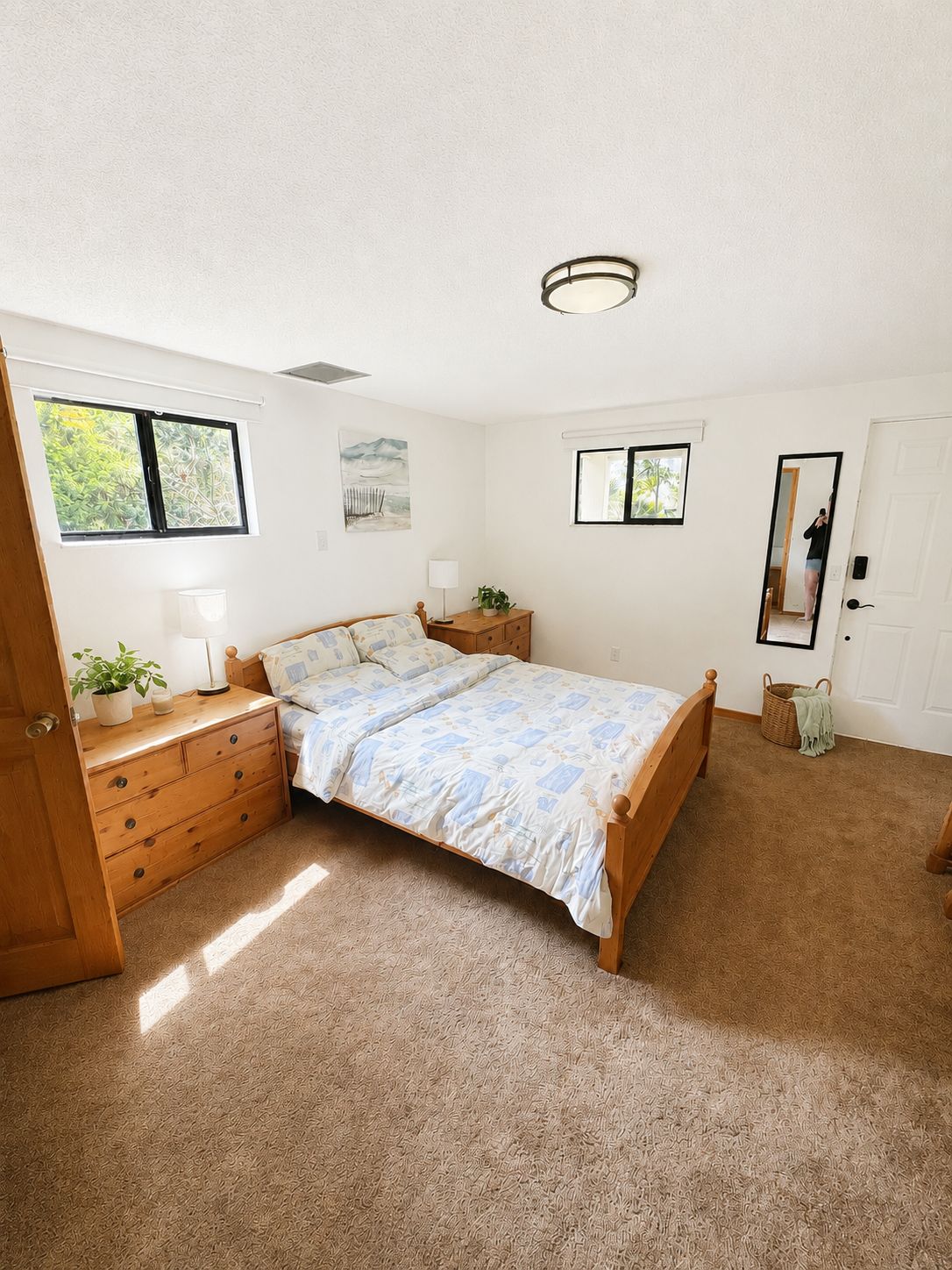 Quarto com cama, mesa de cabeceira, penteadeira, armário, janela, porta e espelho.