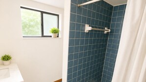 Ein Badezimmer mit Dusche, einem Fenster mit Pflanze und einem weißen Waschbecken.