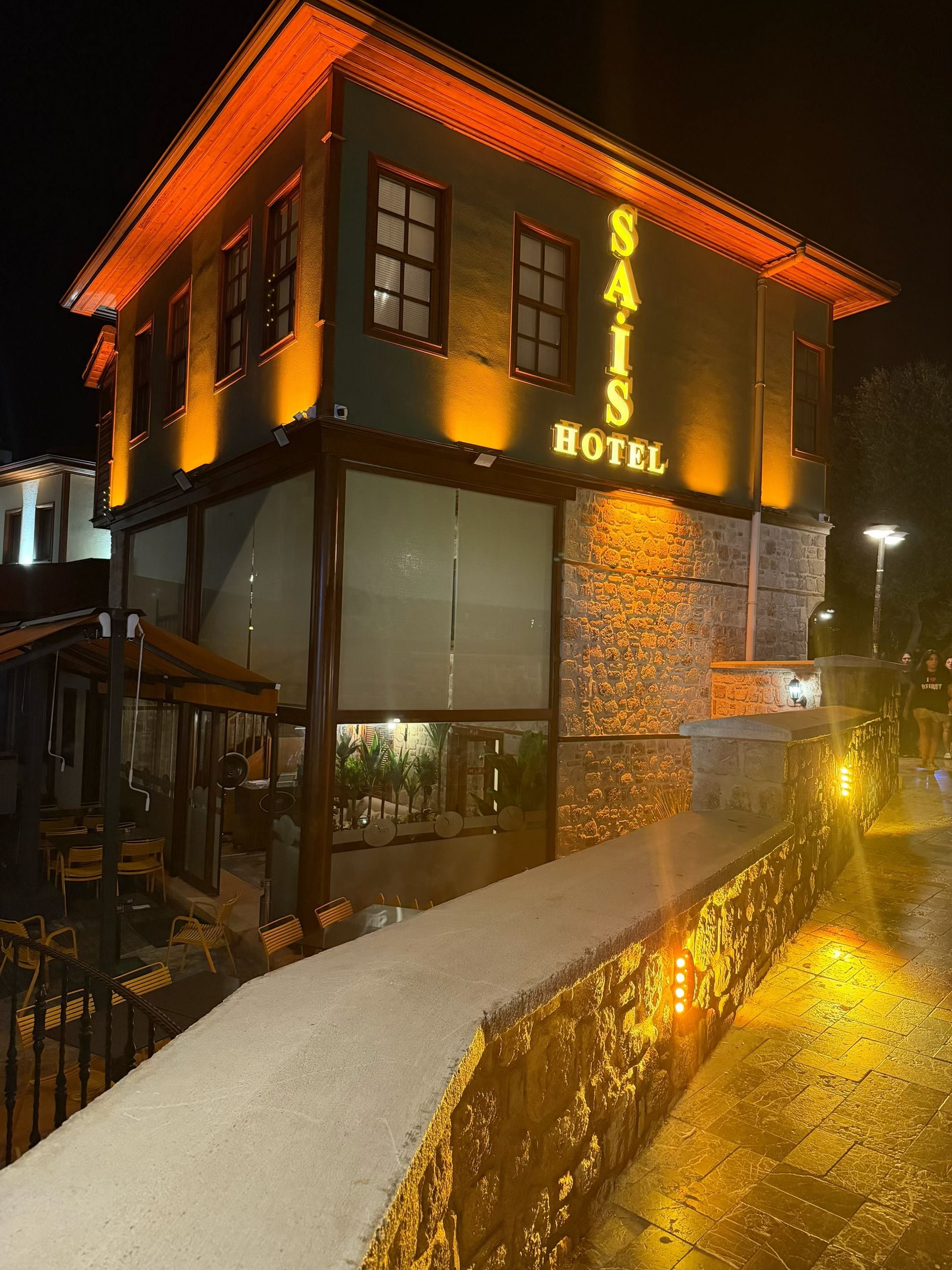 A hotel with a prominent sign, outdoor seating, and a stone facade.