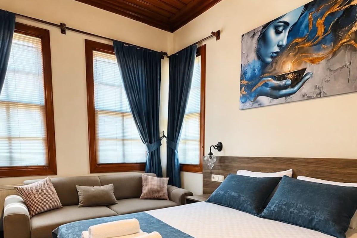 Une chambre à coucher avec un lit, un canapé et un tableau accroché au mur.