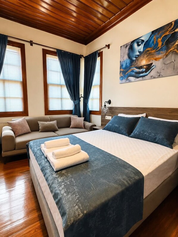Une chambre à coucher avec un lit, un canapé et un tableau accroché au mur.