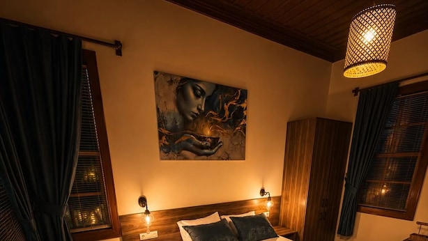 A bedroom with a bed, a sofa, a painting on the wall, and a hanging light fixture. - Sais Hotel Kaleiçi (Antalya)