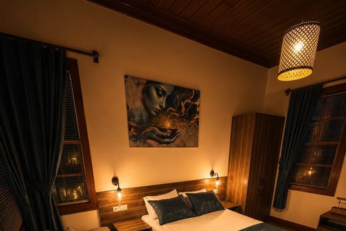 Ein Schlafzimmer mit einem Bett, einem Schlafsofa, einem Gemälde an der Wand und einer Hängelampe.
