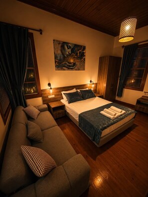 Une chambre à coucher avec un lit, un canapé, un tableau au mur et un luminaire suspendu.