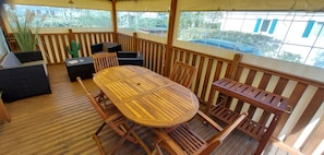 A wooden deck with a round table and chairs, a cactus decoration, and a view of the outside. - 🌊 Fully equipped mobile home for 4 people – SIBLU Mimizan Plage (Mimizan)