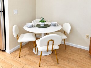 A dining area with a round table, white chairs with wooden legs, and a small potted plant on the table. - The Solace • 22nd-Floor Retreat • Luxury River District • Pool + Skyline Views (Fort Myers)