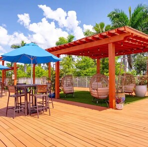 Eine Außenpatio-Terrasse mit Holzboden, Tischen, Stühlen und einer roten Pergola.