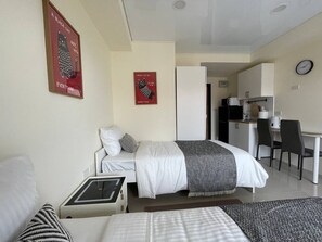 A hotel room with a bed, bedside table, and a desk with a chair. - Studio apartment in tranquil Tambon Mai Khao with AC (Tambon Mai Khao)