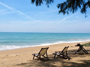 A beach with three wooden lounge chairs facing the ocean. - Studio apartment in tranquil Tambon Mai Khao with AC (Tambon Mai Khao)