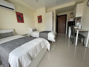 Ein Hotelzimmer mit zwei Betten, einem Schreibtisch und einer Küchenzeile.