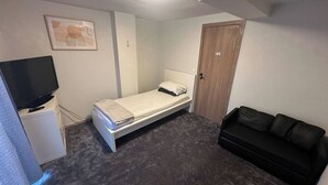 A compact room with a bed, a television, a wardrobe, and a couch. - Charming Apartment in Center of Lier (Lier)