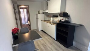 A compact kitchen with a dining area, a refrigerator, a sink, and a black cabinet. - Charming Apartment in Center of Lier (Lier)