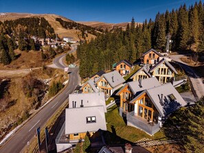 A residential area with houses, a winding road, and a forested hillside. - Chalet #7 With 3 Bedrooms and Sauna (Oberwölz)