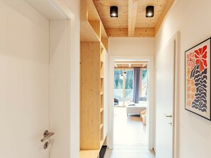 Un couloir avec un plafond en bois, une porte dotée d’un trou de serrure et une œuvre d’art encadrée accrochée au mur.