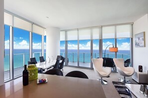 Une chambre d’hôtel moderne dotée d’un grand balcon, d’un coin repas et offrant une vue sur l’océan.